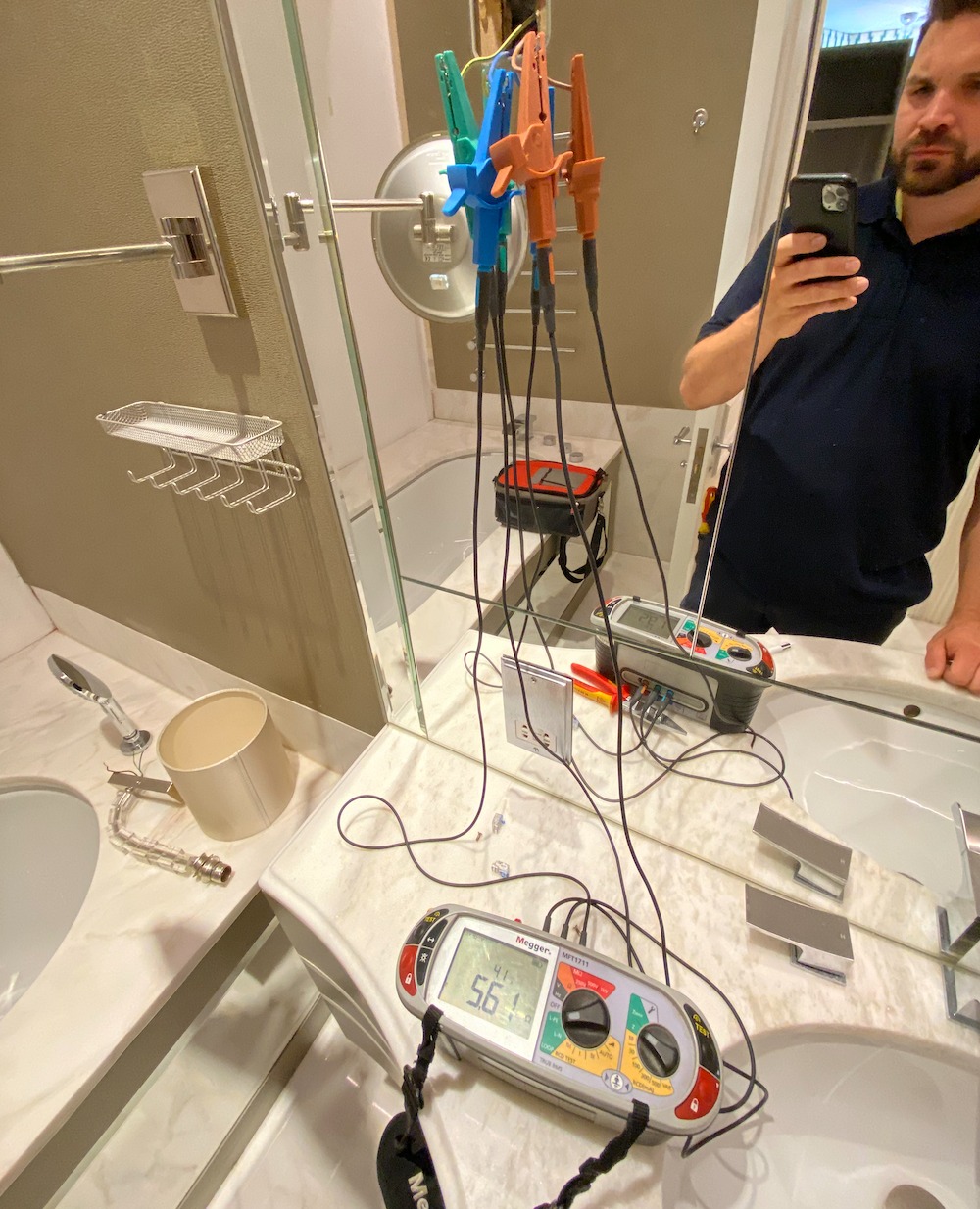 Testing circuits in a marble bathroom with leads and a tester on the vanity