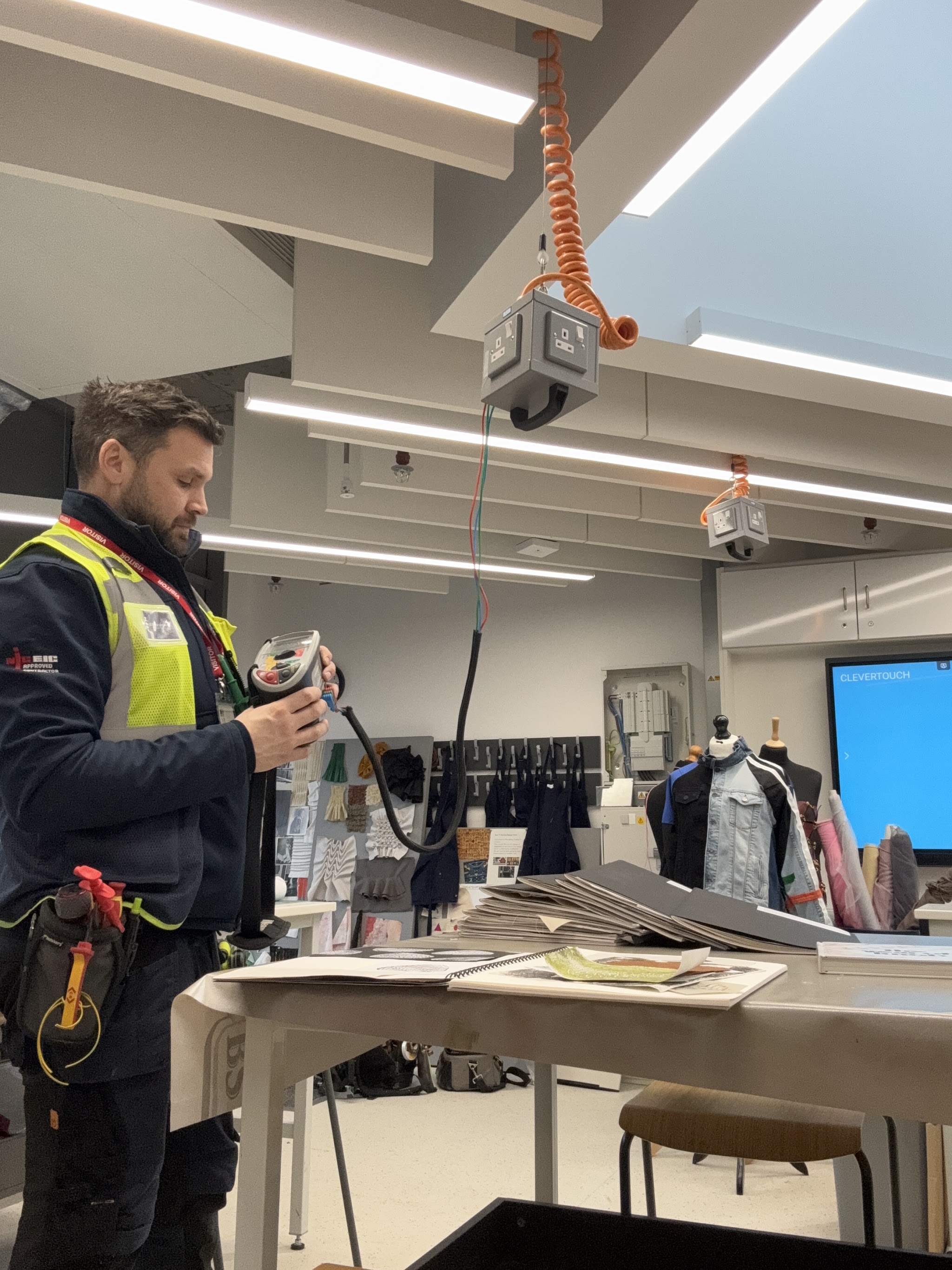 RB Response electrician in hi-vis testing circuits in a commercial studio with track lighting