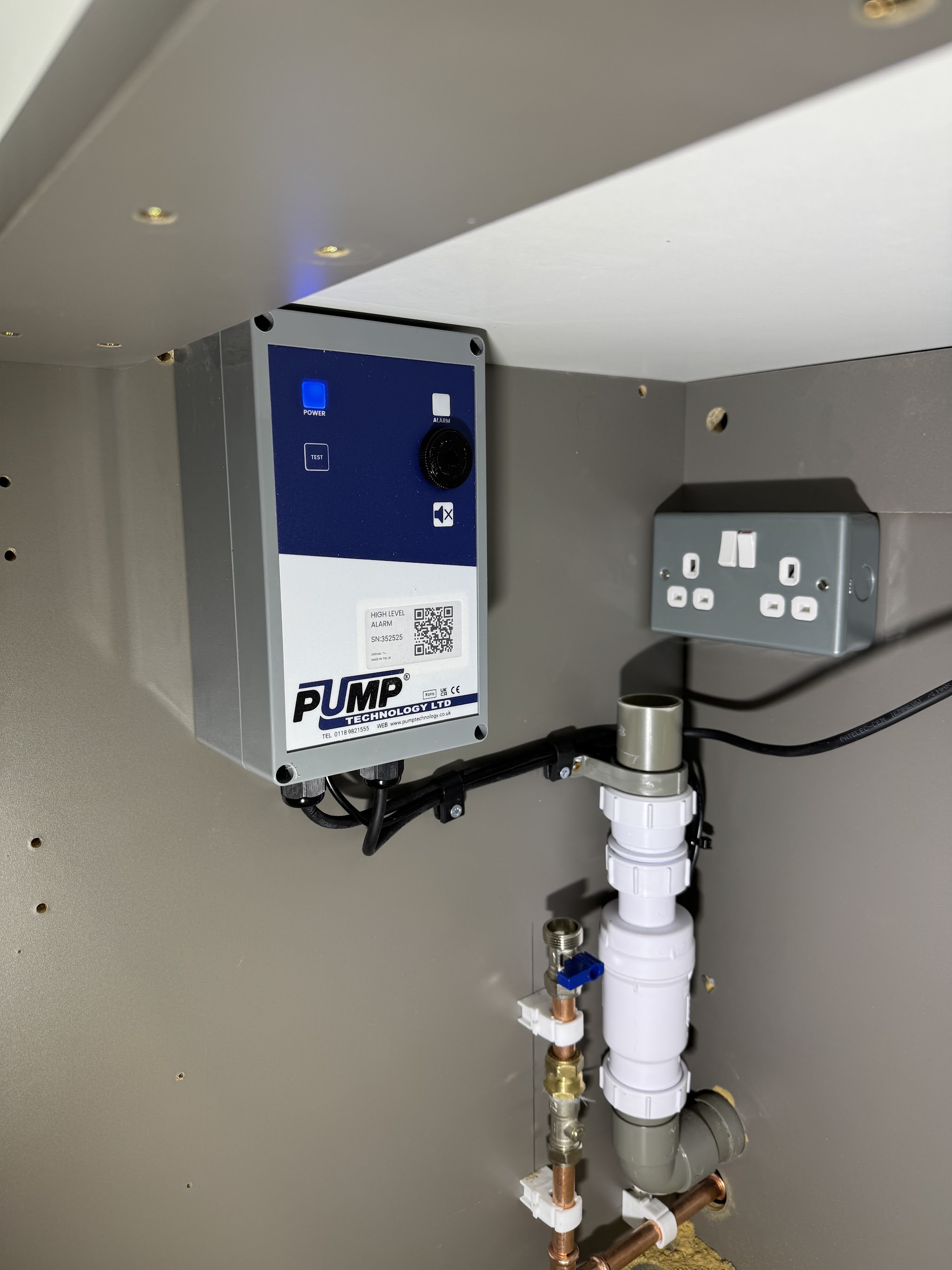 Pump control unit wired in beside a switched socket in a fitted cupboard